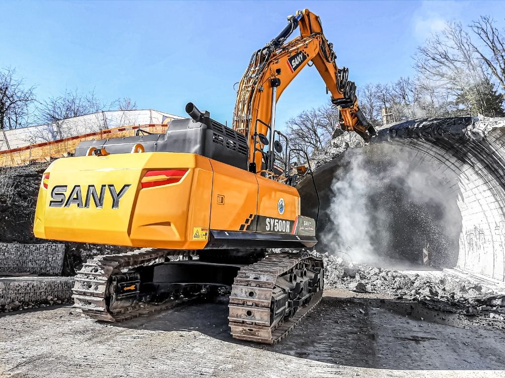 SANY SY500H bandgrävare river en betongkonstruktion vid tunnelöppning.
