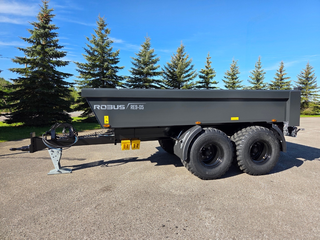 Robus dumpervagn RE9-05 i sidovy med två axlar och grovmönstrade däck, parkerad på asfalt med granar i bakgrunden.